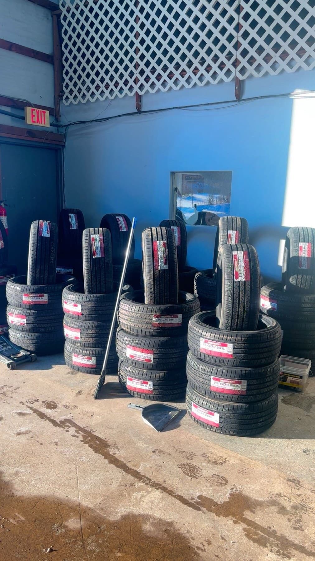 Stacks of brand new labeled tires against the blue shop wall