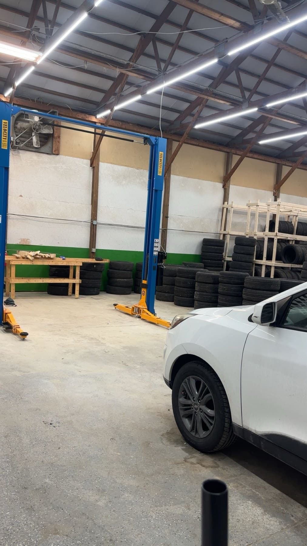 Two-post lift and an SUV inside the Speedy Tires service bay
