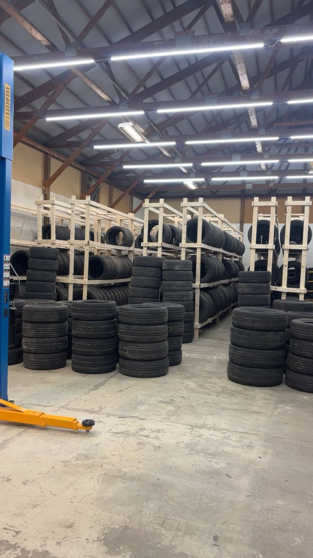 Rows of stacked tires and tire racks inside the Speedy Tires warehouse